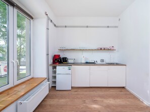 Une cuisine compacte équipée d’un réfrigérateur intégré, d’une machine à café et d’un grille-pain.