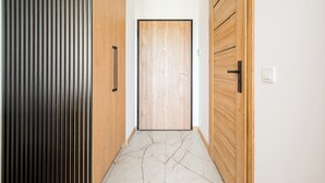 Un couloir avec une porte en bois, un panneau à rayures verticales et un sol en marbre.