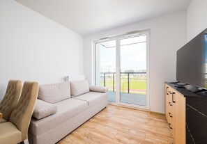 Een moderne woonkamer met een bank, televisie en houten vloer.