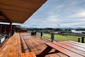 Eine Holzterrasse mit einem Picknicktisch und Blick auf einen See und Berge.
