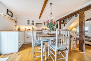 A kitchen with white cabinets, a wooden dining table, and chairs. - Cottage Sleeps 4 with Enclosed Garden (Henley-on-Thames)