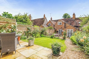 A garden with a patio, wicker furniture, and a brick house. - Cottage Sleeps 4 with Enclosed Garden (Henley-on-Thames)