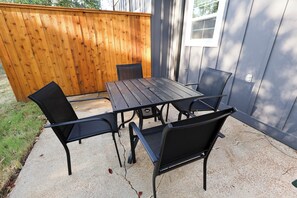 Eine Terrasse mit Holzzaun, Tisch und vier Stühlen.