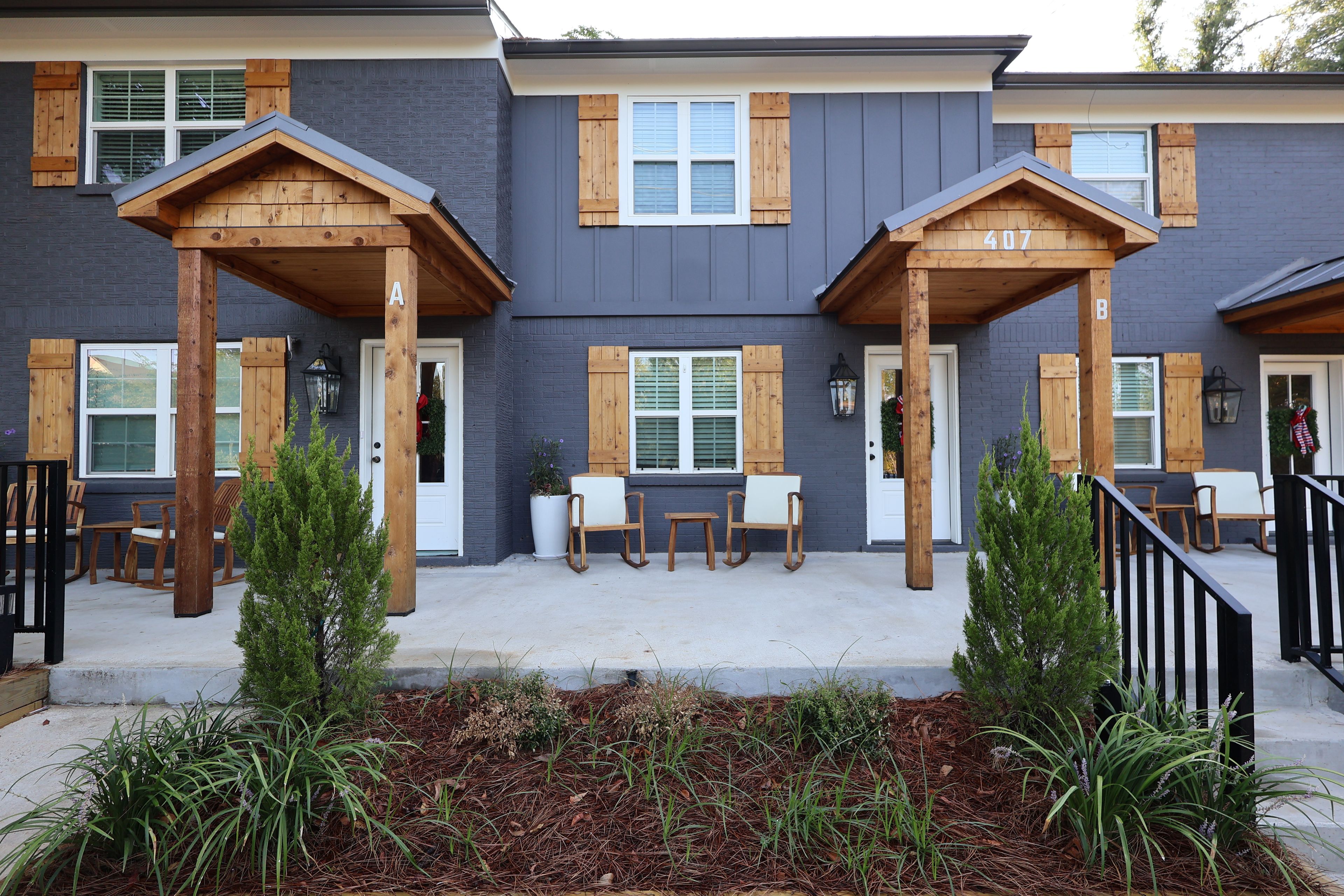 A building with a grey exterior, wooden porch columns, and a number '407' on the wall.