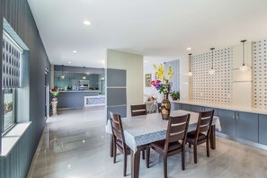 Uma área de jantar moderna com uma mesa de mármore, cadeiras de madeira e um vaso de flores.