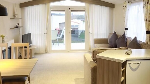A spacious living area with a sofa, a dining table, and a TV. - Ty Newydd Leisure Park 2-Bed Caravan, Sleeps 6 (Llanbedrgoch)