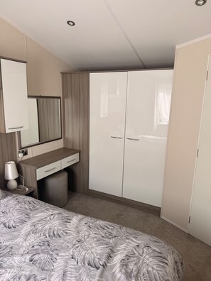Ein Schlafzimmer mit Bett, Nachttisch mit Lampe, Kommode und Kleiderschrank.