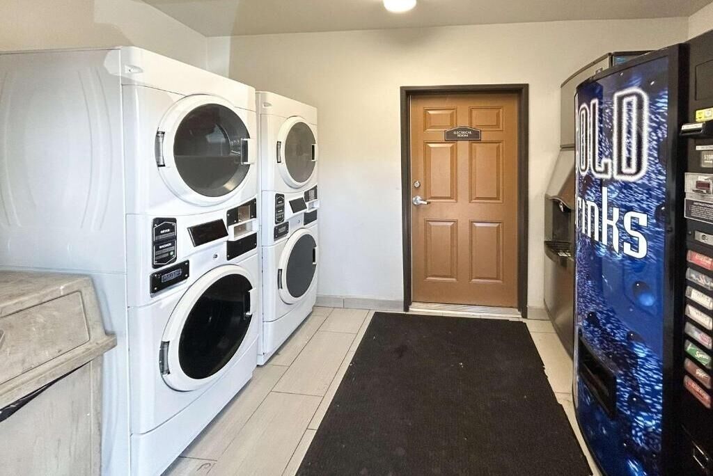 A laundry room with multiple washing machines, a door labeled 'Electrical,' and a vending machine labeled 'Cold Drinks.'