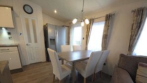 Et kompakt køkken med et køleskab, et spisebord med stole og en sofa.