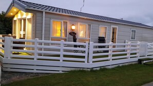 En campingvogn med hvidt hegn, en veranda med stole, og et skilt der siger 'Lake Tahoe'.