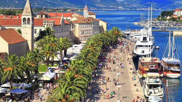 A coastal promenade with a historic building, palm trees, and a marina with boats. - Traditional apt in stone house in heart of Trogir (Trogir)