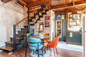 A rustic interior with a wooden staircase, a dining area with chairs, and a kitchen area. - Traditional apt in stone house in heart of Trogir (Trogir)
