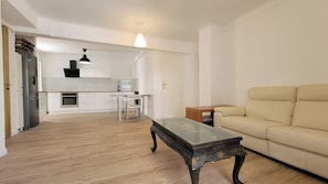 Un salon avec un canapé, une table basse et une cuisine en arrière-plan.