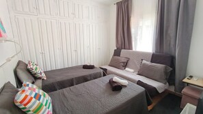 Ein Schlafzimmer mit zwei Betten, einem Schlafsofa, einem kleinen Tisch und einem Kleiderschrank.