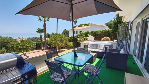 A balcony with a table, chairs, a grill, and an umbrella. - House - Sleeps 8 - Hot Tub - Beach Access (URBANIZACION BUENAS NOCHES)