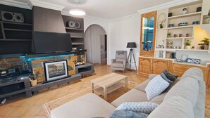 A modern living room with a fireplace, a sofa, a coffee table, and a TV. - House - Sleeps 8 - Hot Tub - Beach Access (URBANIZACION BUENAS NOCHES)