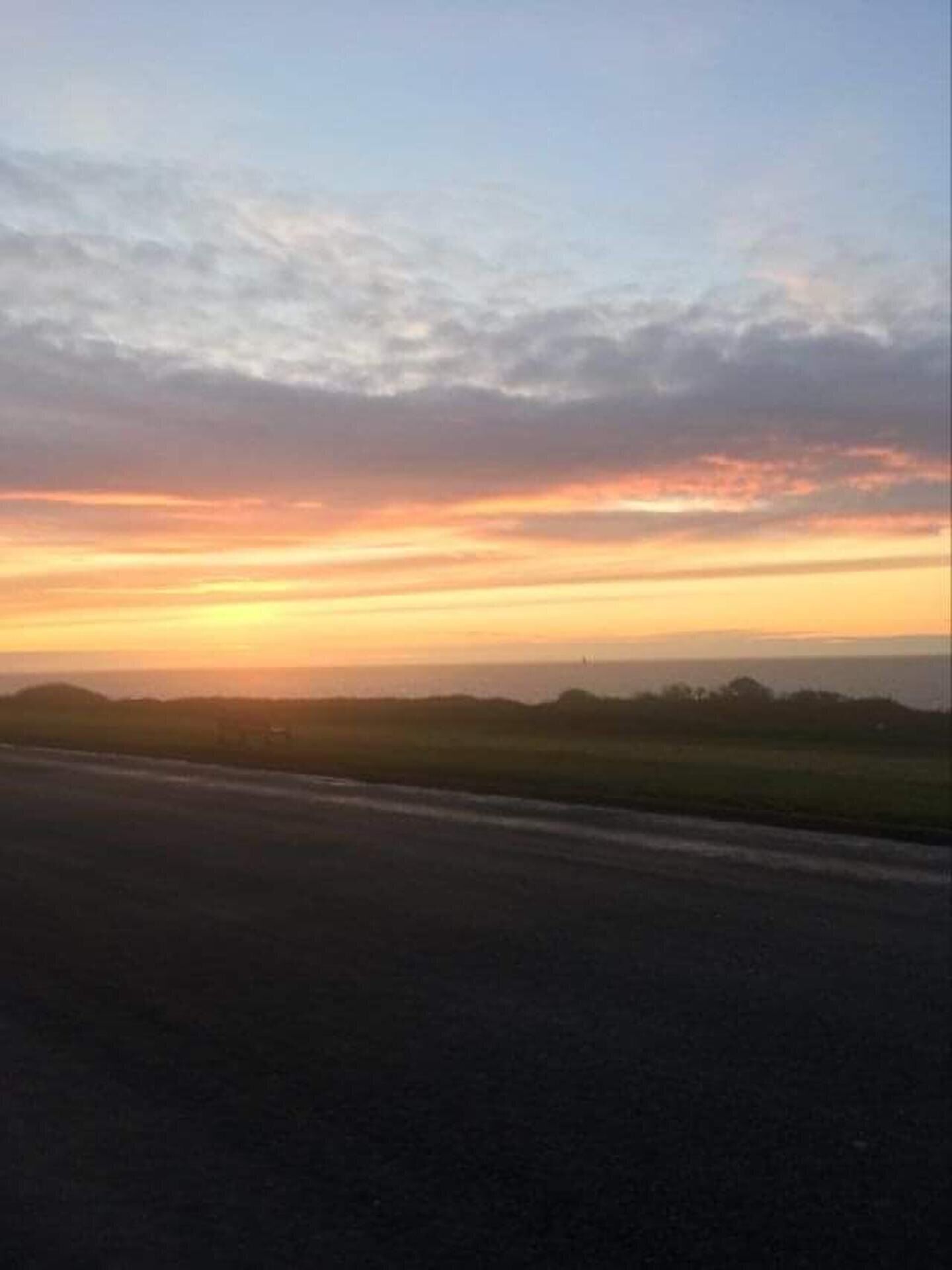 Un atardecer sobre una llanura, con una carretera en primer plano.