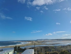 A coastal landscape with a clear sky, a beach, and a few buildings.