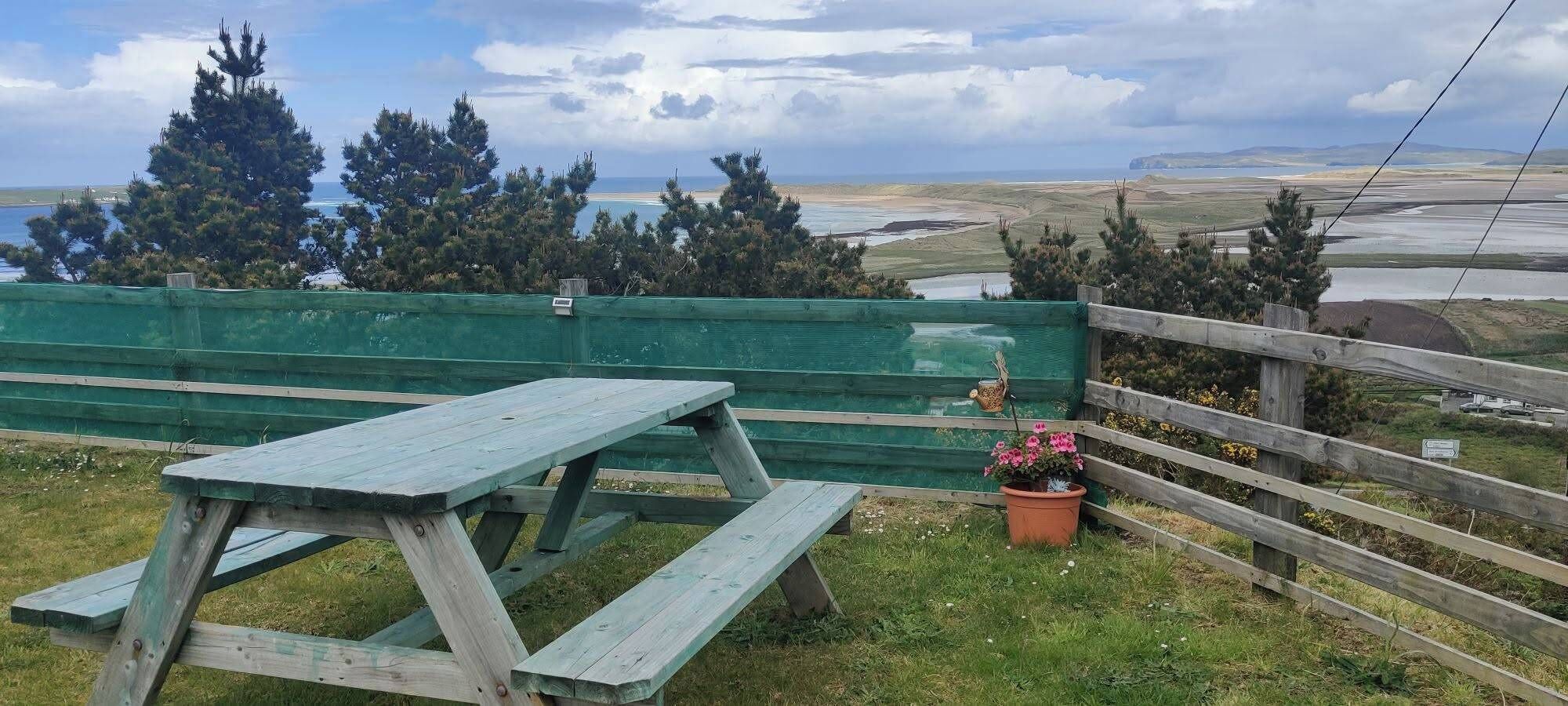 A picnic table with a view of a coastal landscape.