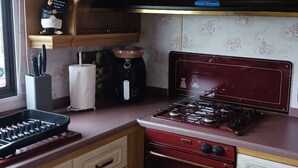 Keittiössä on punainen liesi, kahvinkeitin ja veitsiteline.