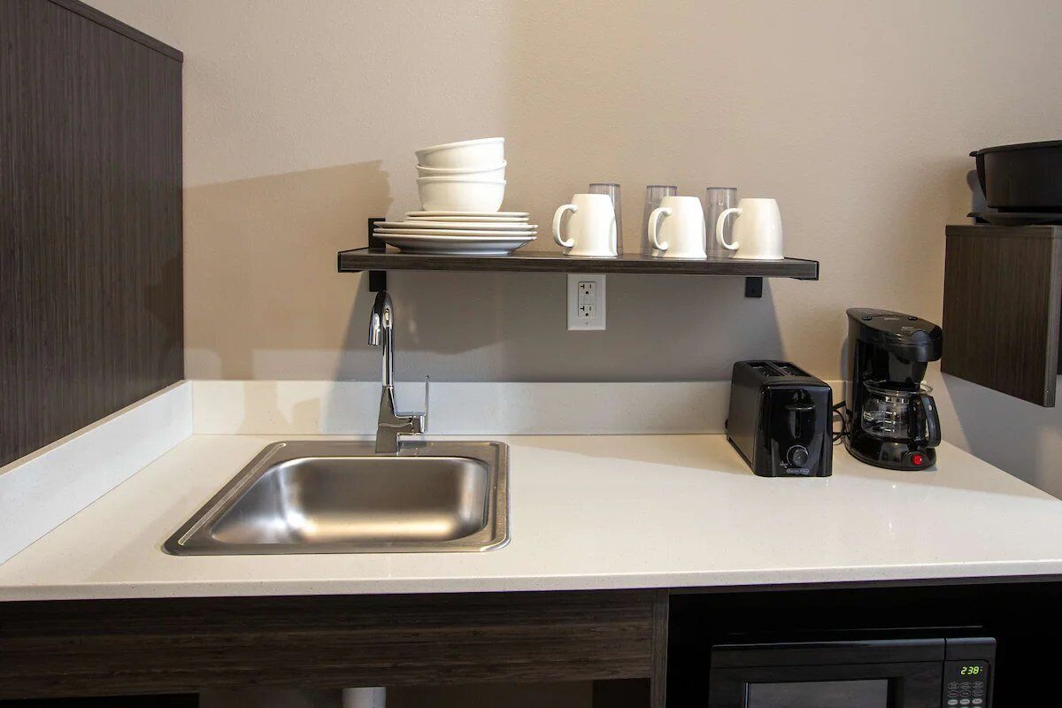 A kitchen with a stainless steel sink, a coffee maker, and a toaster on the counter.