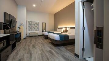 A hotel room with a bed, bedside table, lamp, and a desk with a chair.