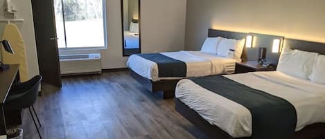 A hotel room with two beds, a desk, a chair, a mirror, and a window.