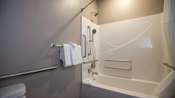 A bathroom with a bathtub, a toilet, a shower area, and a towel rack.