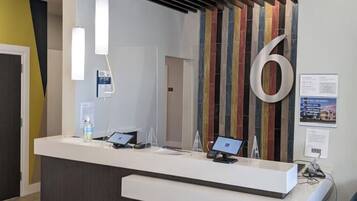 A reception desk with a large number '6' sign, a computer, and a water bottle.