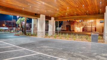 An outdoor covered area with a wooden ceiling, concrete floor, and a trash bin.