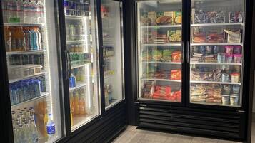Una sección de una tienda con congeladores etiquetados 'Cold Drinks' y 'Frozen Food'.