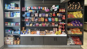 Un présentoir bien organisé, proposant une sélection de collations et de boissons, dans un magasin doté de plusieurs étagères et d’une grande variété de produits.