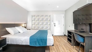 A modern hotel room with a bed, a desk, a chair, and a TV. - Ideal Retreat for Exploring Local Sights | Steps to Weber Point Events Center (Stockton)