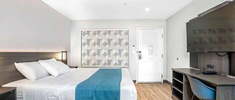 Una habitación de hotel moderna con cama, escritorio, silla y televisor.