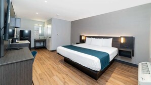 Une chambre d’hôtel moderne équipée d’un lit, d’un bureau, d’une télévision et d’un miroir.