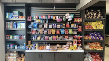 Velorganiseret udstilling af snacks og drikkevarer i en butik med flere hylder og et bredt udvalg af produkter.