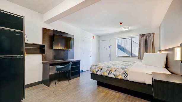 Ein modernes Hotelzimmer mit Bett, Schreibtisch und Kleiderschrank.