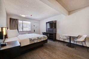 A hotel room with a bed, desk, TV, and two chairs. - The Perfect Balance of Adventure & Elegance w/ Free Parking | Pets Allowed (Rock Springs)