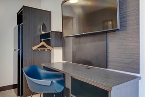 A room with a desk, a chair, a wardrobe, and a mirror.