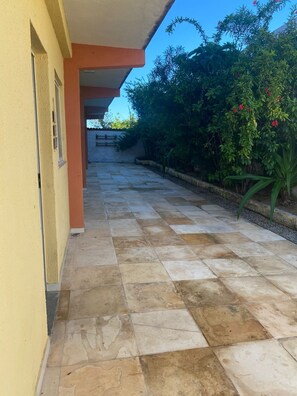Un sendero pavimentado que conduce a un edificio con fachada amarilla y techo naranja.