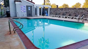 A swimming pool with a lifeguard chair, a no diving sign, and a pool warning sign.