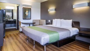 A hotel room with a bed, bedside tables, a desk, and a chair.