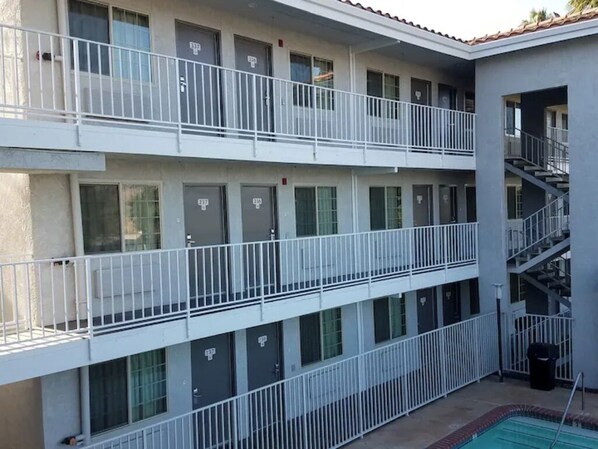 A multi-story building with balconies, a pool, and a staircase.