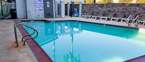 Una piscina con un asiento de socorrista, un cartel de prohibido bucear y un cartel de advertencia para la piscina.