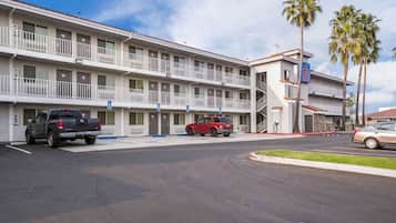 A motel with a two-story structure, a parking lot, and a few vehicles.