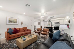 A living room with a sofa, chairs, a coffee table, and a kitchen in the background. - Unique 3-bedroom house in beautiful Chandler with cool AC comfort, huge backyard (Chandler)