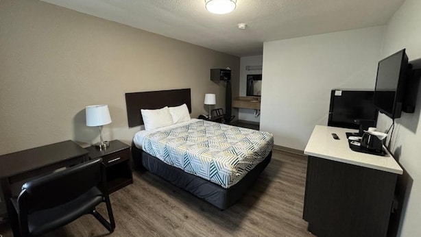 A hotel room with a bed, desk, chair, TV, and a kitchenette area. - Smart Choice for Budget-Conscious Travelers Near Dinings | City Sandwich -0.1 mi (Clark County)