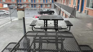 A rooftop patio with a picnic table and a metal grill.