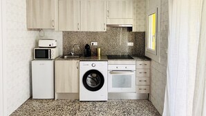 Cocina compacta con lavadora, microondas y horno.