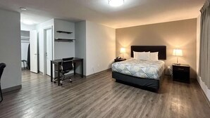 Quarto de hotel com cama, mesas de cabeceira, escrivaninha e uma cadeira.